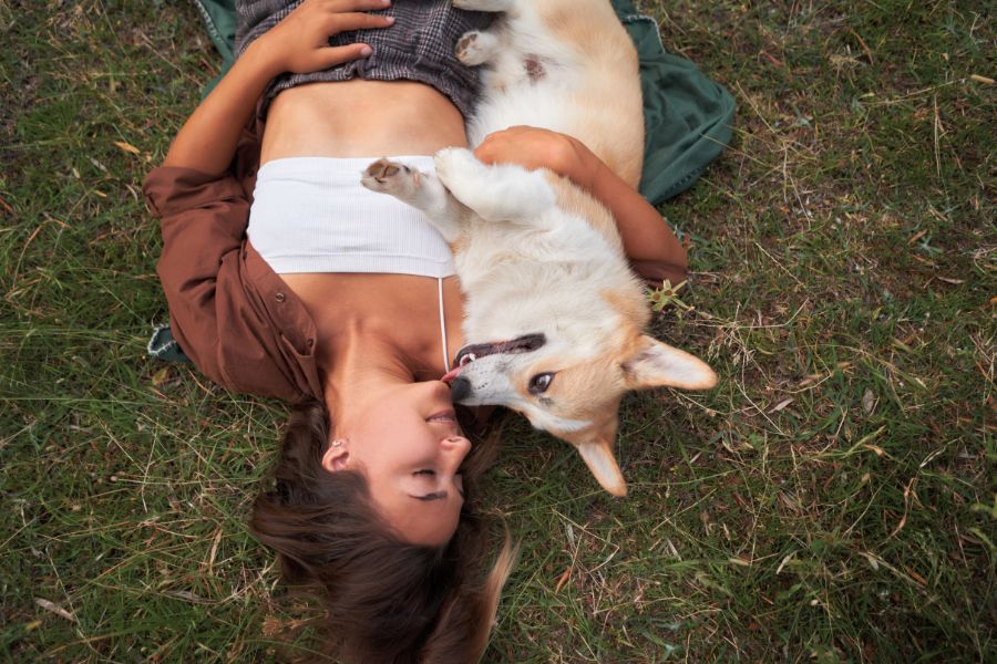 una ragazza e il suo cane si scambiano baci e leccatine distesi su un prato