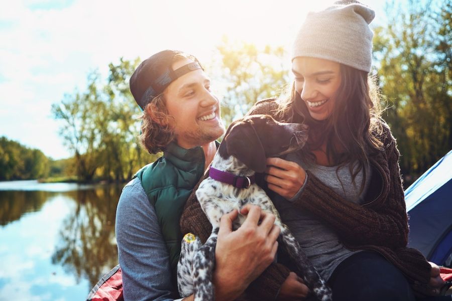 una ragazzo e una ragazza abbracciano un cane sulle rive di un lago