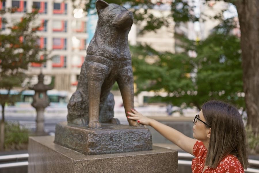 Una donna tocca la zampa della statua di Hachiko alla Stazione di Shibuya di