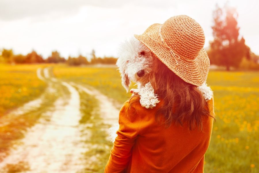 una ragazza tieni in braccio la sua cagnolina mentre passeggia in un sentiero