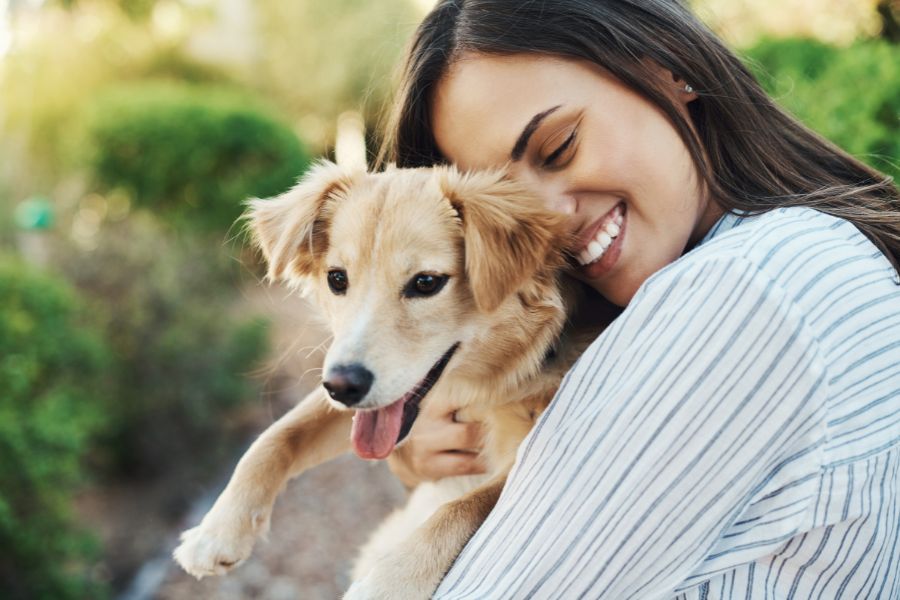 Una ragazza abbraccia affettuosamente un cane felice